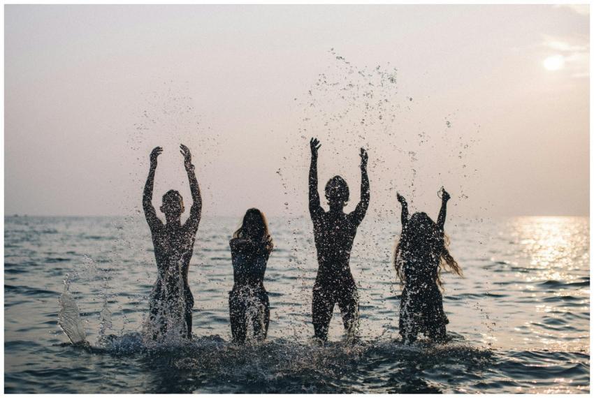 Silhouettes of four people joyfully splashing wate