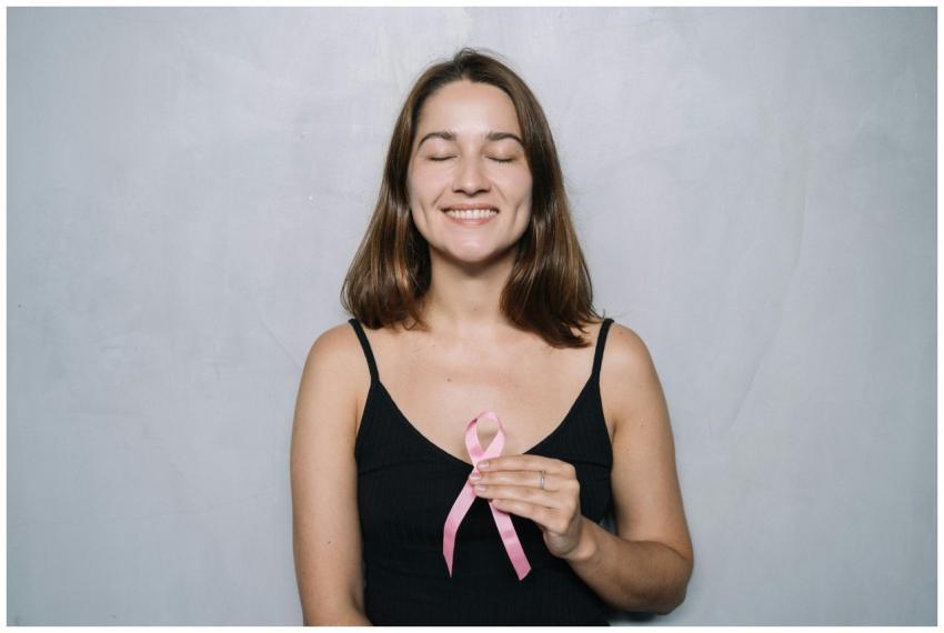 A smiling woman with eyes closed holds a pink brea