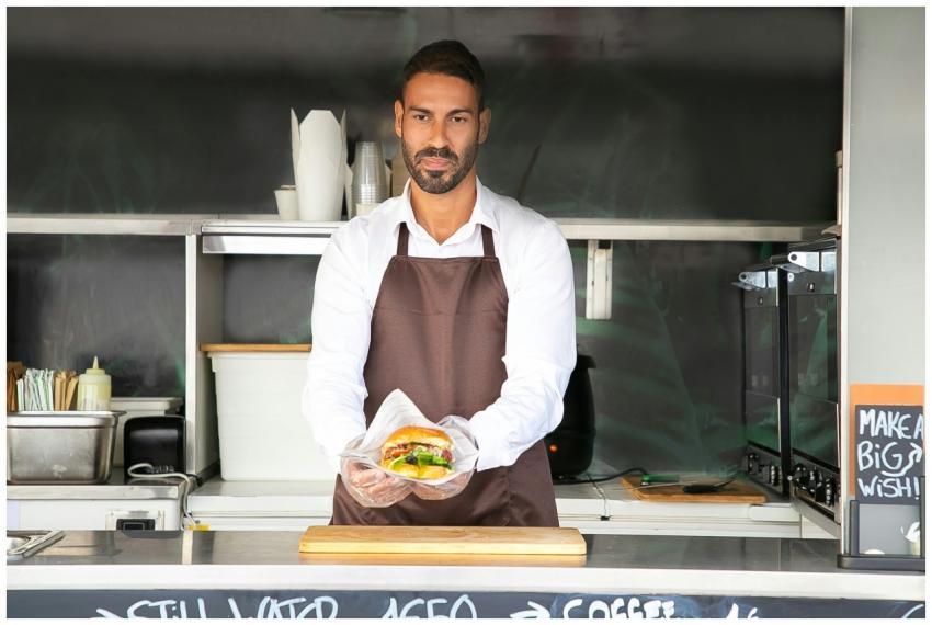 A street food vendor in an apron holding a freshly
