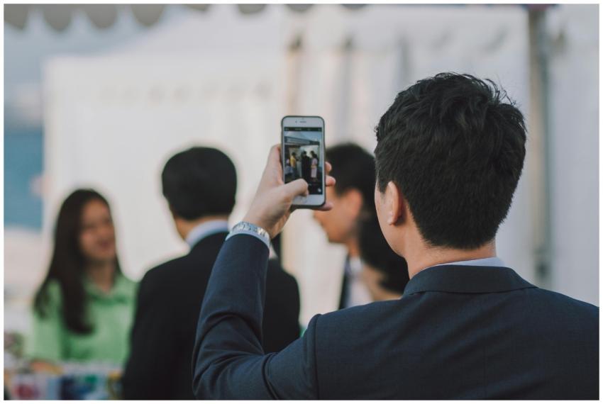 Man in suit photographing colleagues with smartpho