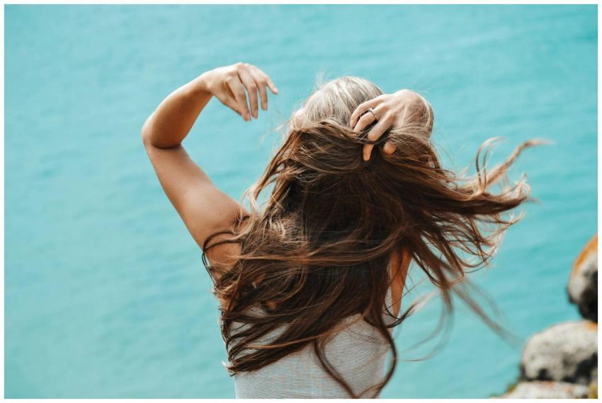 Back view of a woman with flowing hair near the se
