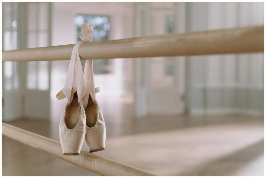 Close-up of ballet pointe shoes hanging on a barre