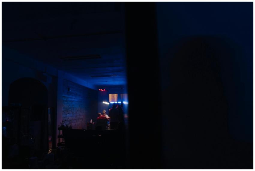 A moody club scene with people sitting in dim ligh