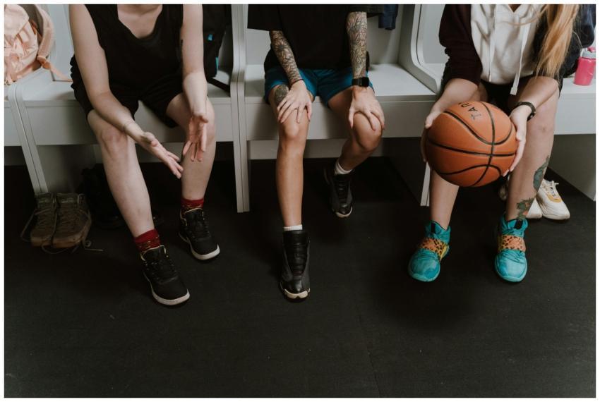 Three women basketball players sitting in a locker