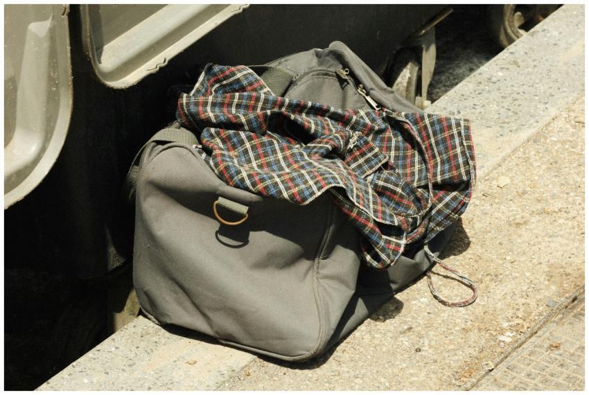 Close-up of a grey travel bag with a plaid shirt,