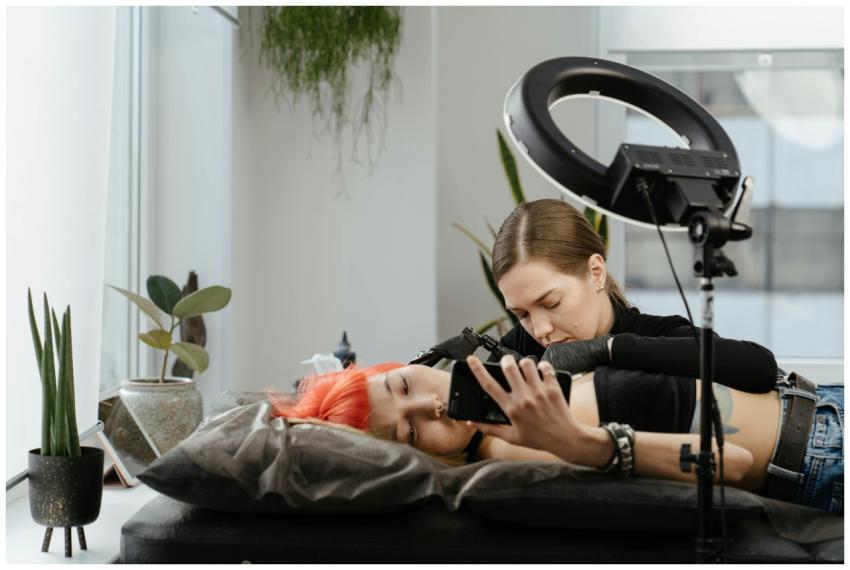 A female tattoo artist creating a design on a clie