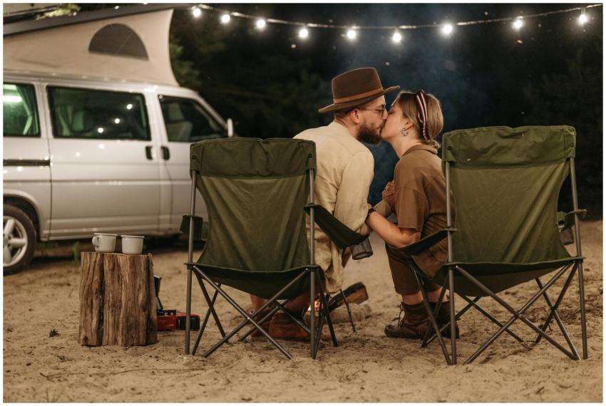 A couple sharing a kiss at a campsite, with a camp