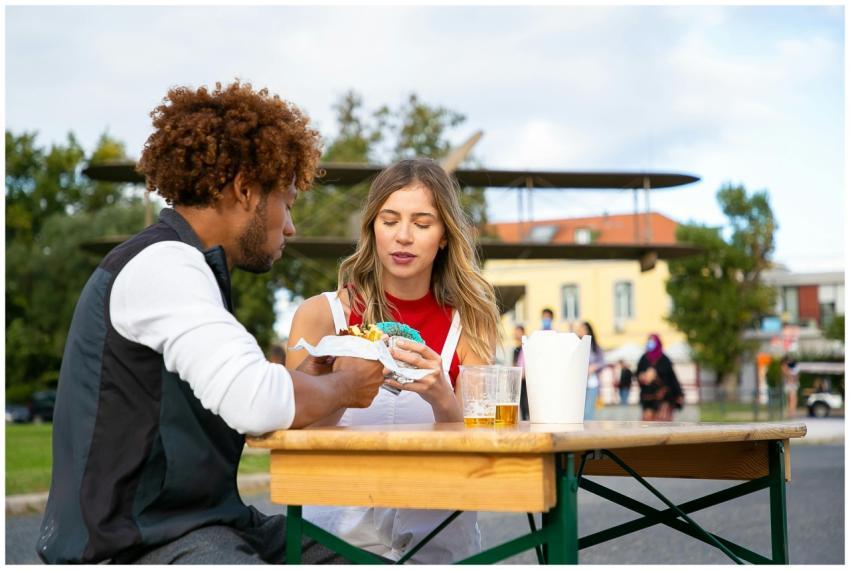 A couple sitting outside enjoying street food and