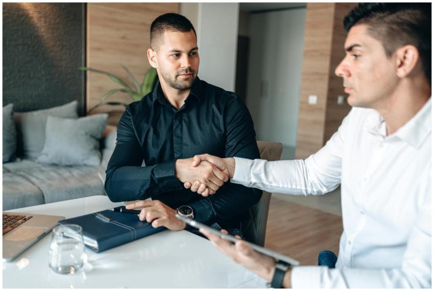 Two businessmen shaking hands over a deal in a mod