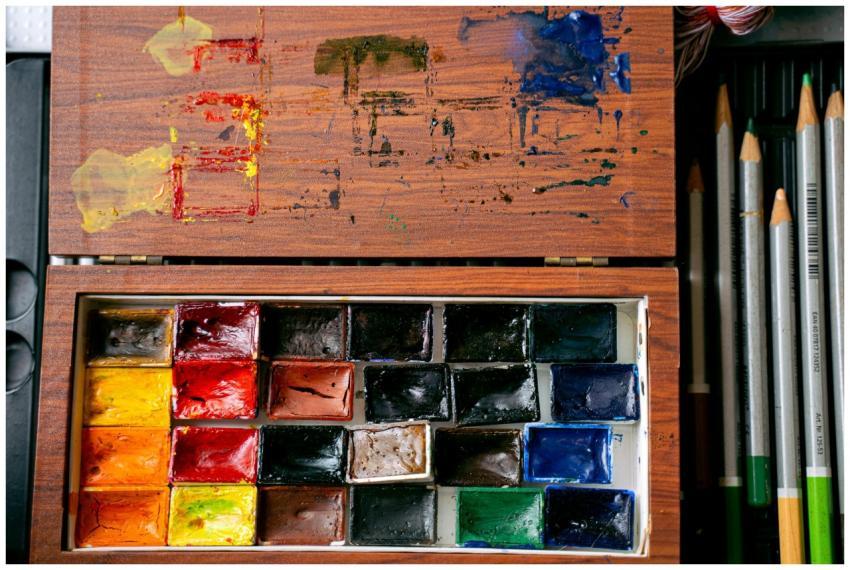 A vibrant watercolor palette and colored pencils d
