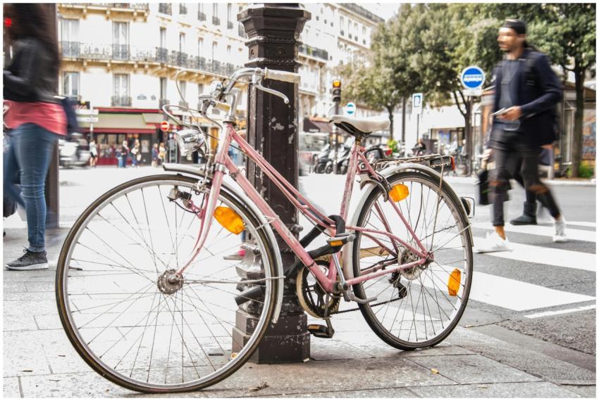 Pink bicycle locked to a post on a bustling Paris