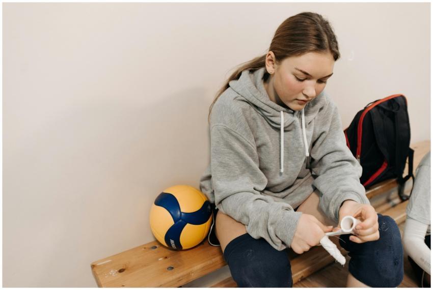Young female athlete in gray hoodie wrapping hands