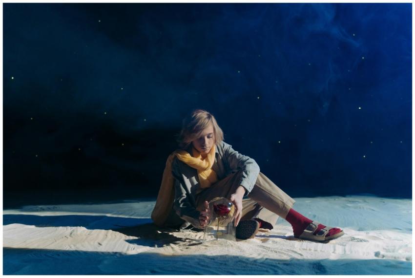 A young person in cosplay sits in a dreamy, starry