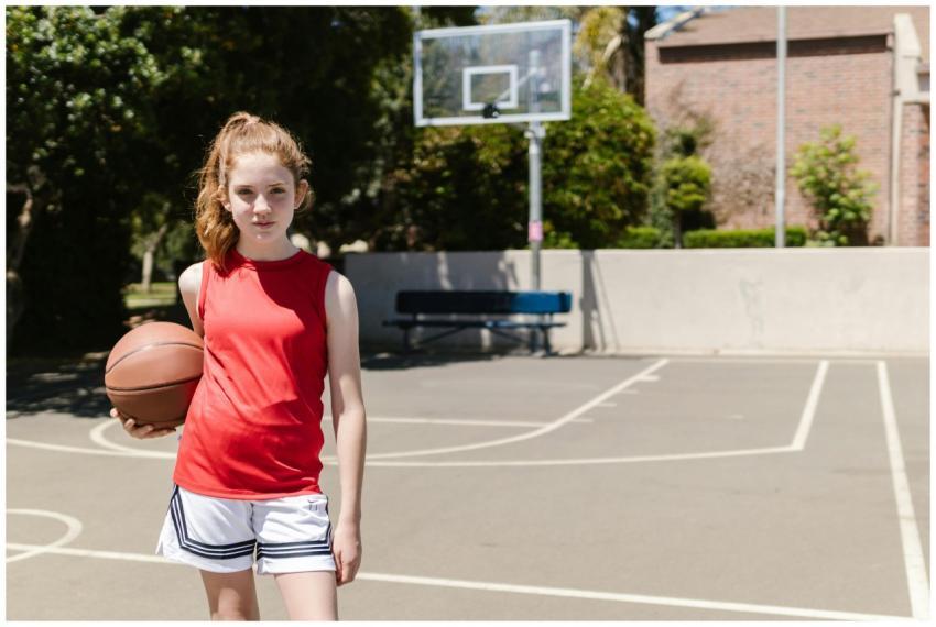 Young girl in red tank top holding basketball on o