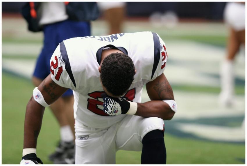 Football player in uniform kneeling before a game,