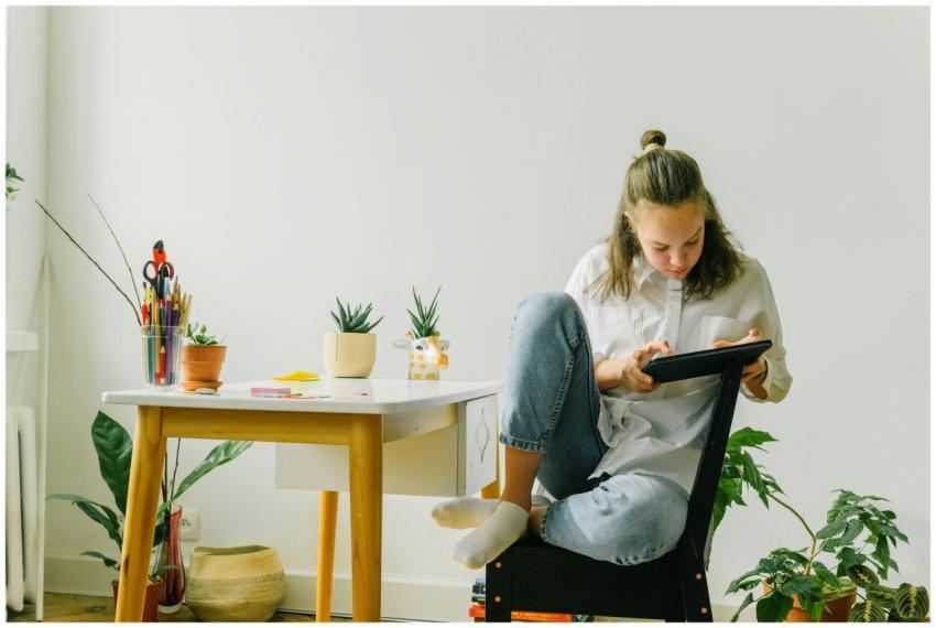 A teenage girl using a tablet while sitting in a m