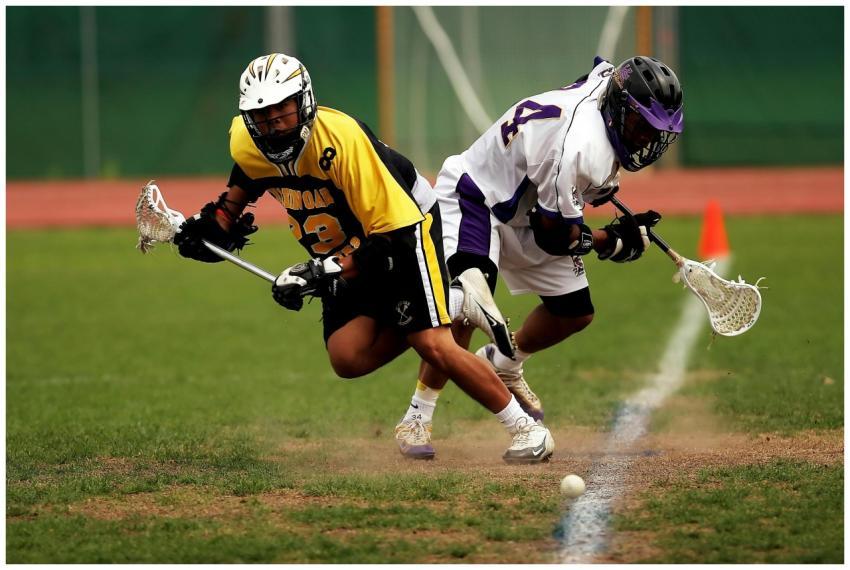 Two men playing an intense lacrosse game outdoors