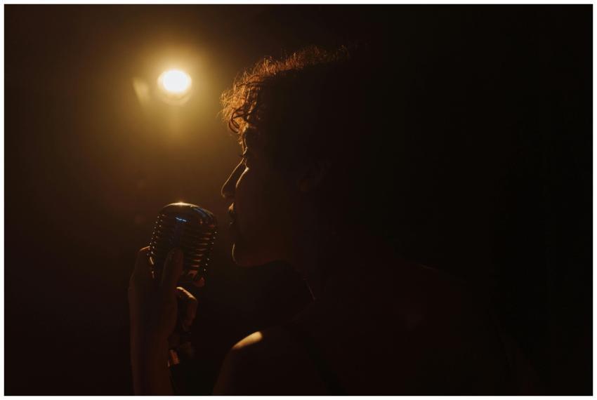 A dramatic silhouette of a performer singing with