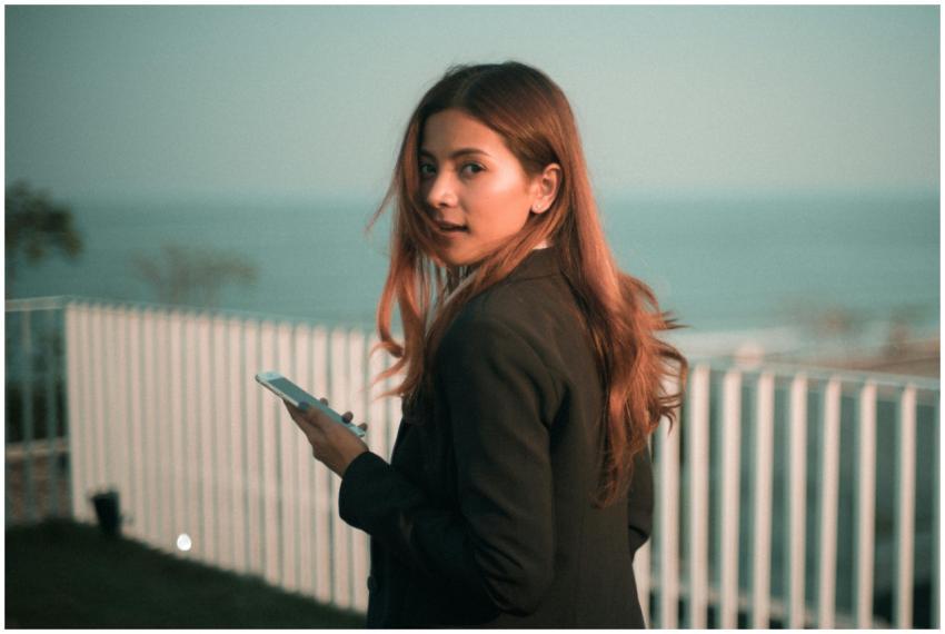 Stylish young woman holds smartphone with a scenic