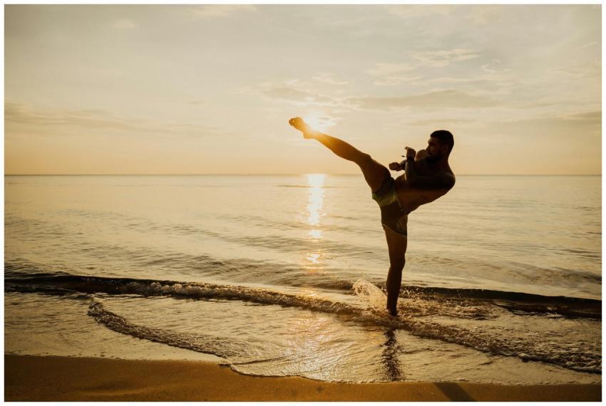 Martial artist performing a high kick on a beach d