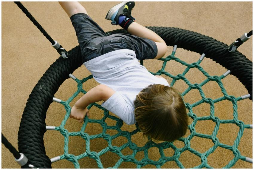 Young boy enjoying a playful moment on a net swing