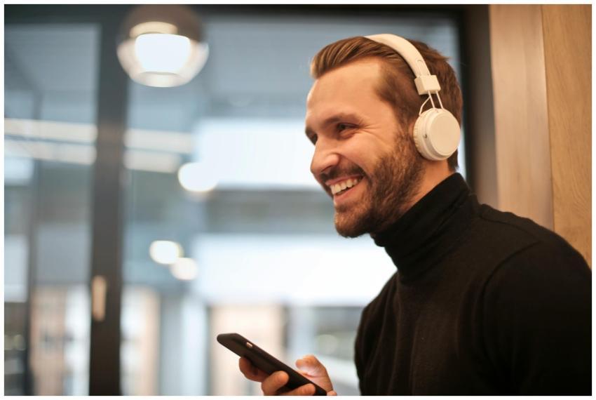 Bearded man smiling with headphones and smartphone