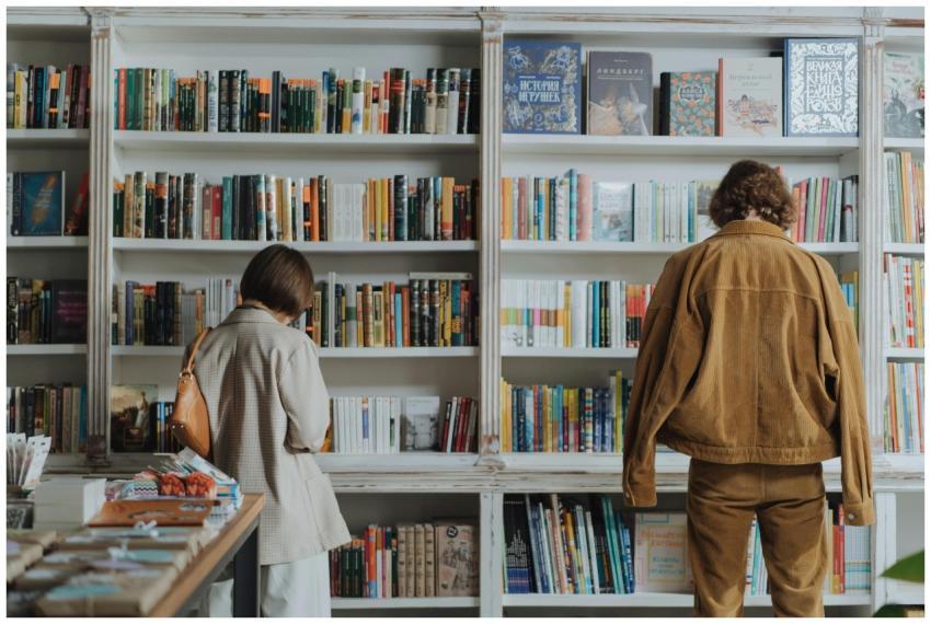 Two adults browsing books in a cozy bookstore, enj