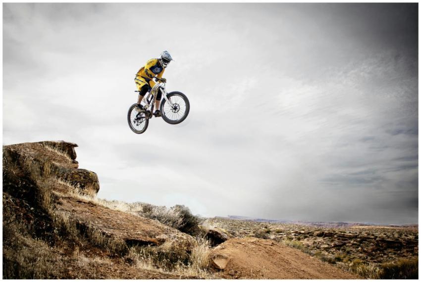 A cyclist performs a daring jump off a rocky cliff