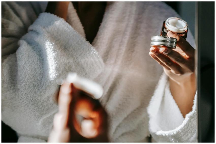 Woman in bathrobe applying skincare cream for a ca