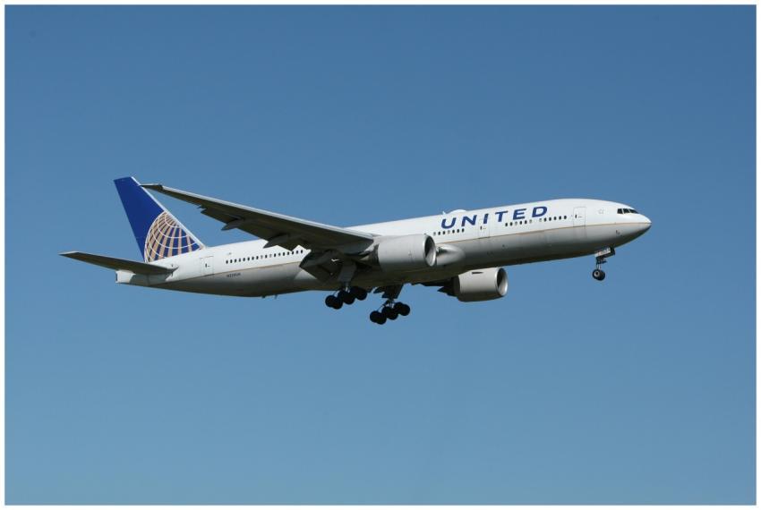 A United airliner flying against a clear blue sky,
