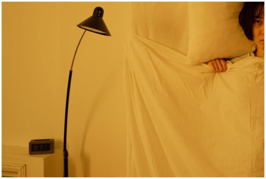 A woman lying awake in bed at 3:33 a.m., showcasin