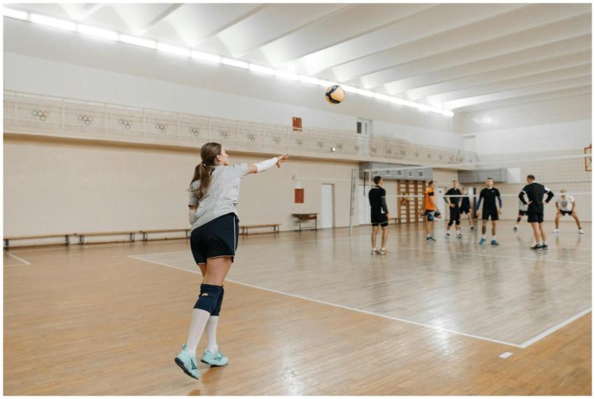 Athletes practicing volleyball indoors, focusing o