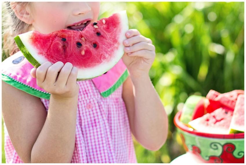 Young girl eating a juicy watermelon slice in a su