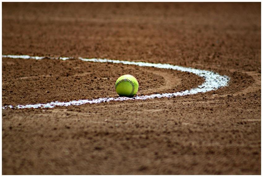 A softball resting on a dirt field with chalk line