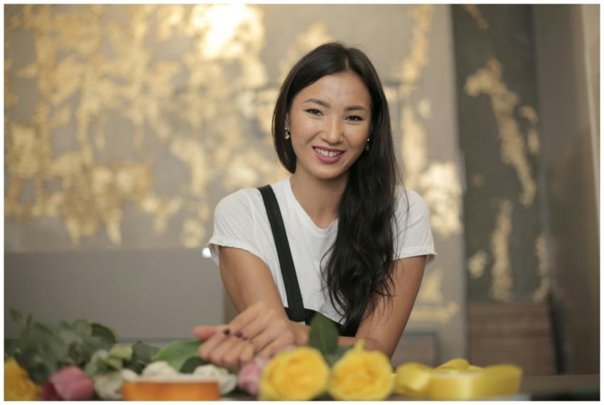 Positive ethnic female florist wearing apron smili