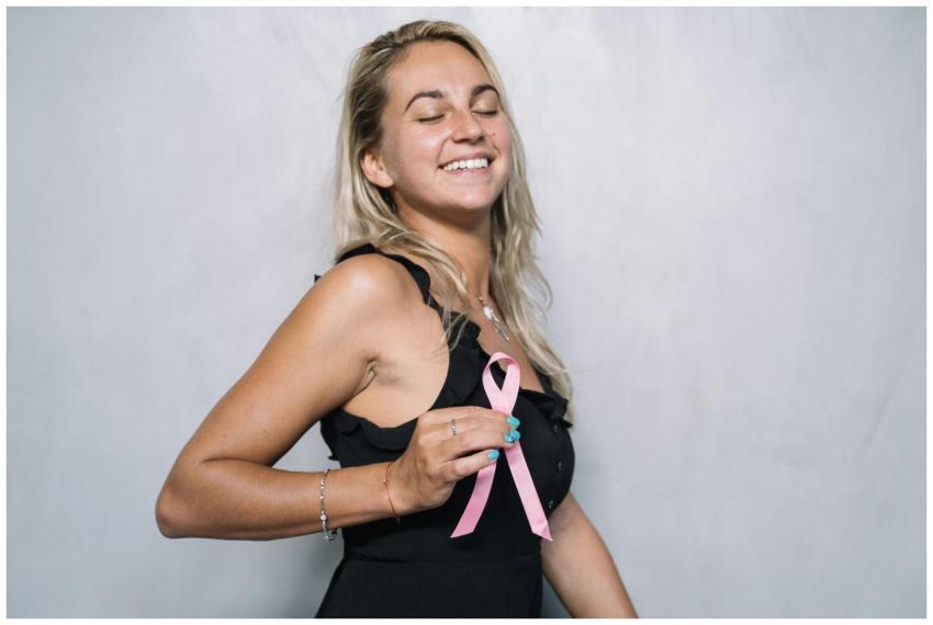 A joyful woman holding a pink ribbon symbolizing b