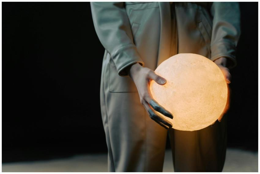 An individual holding a glowing spherical object w