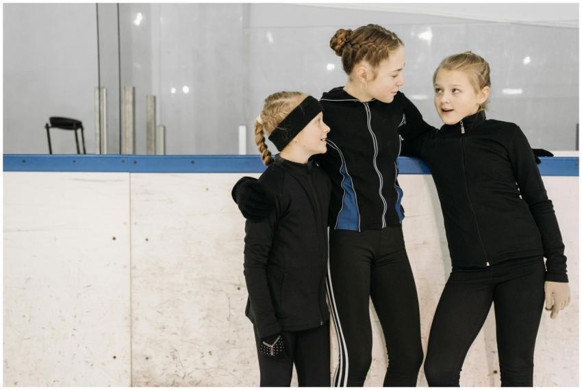 Three young female ice skaters in black jackets st