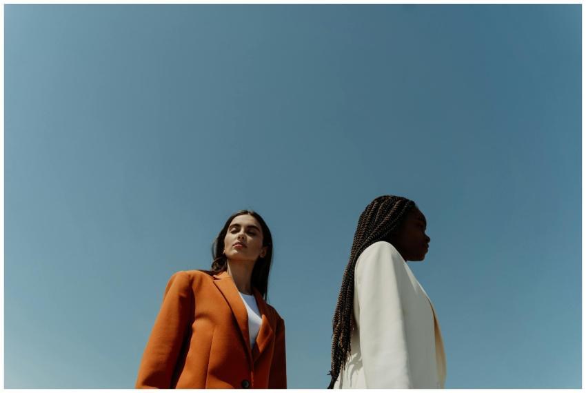 Two stylish women in corporate attire against a bl