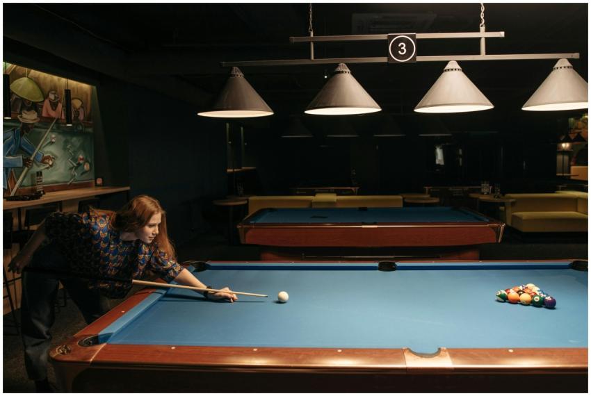 Woman enjoying a game of billiards in a dimly lit