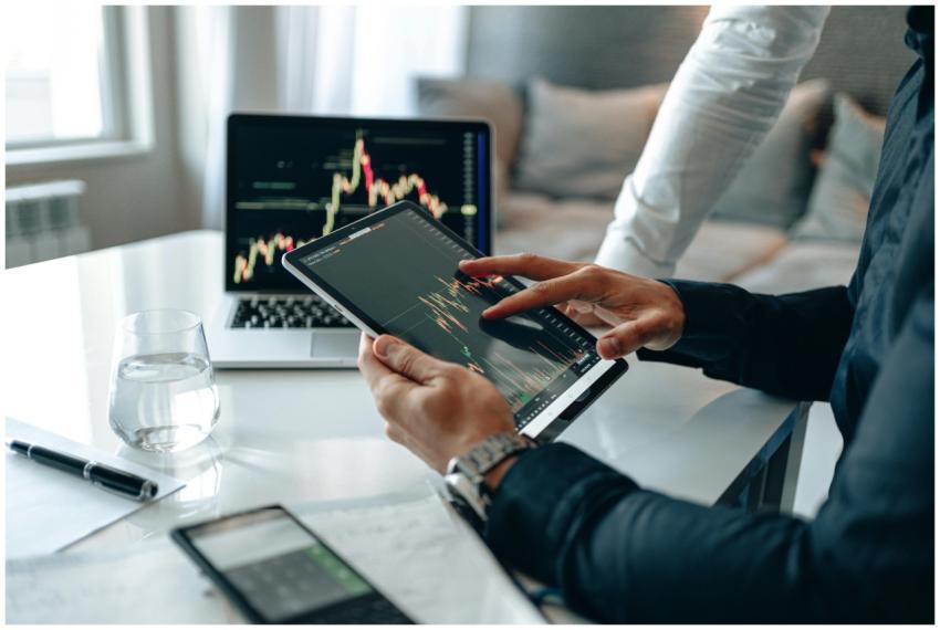 Two professionals using a tablet and laptop to ana