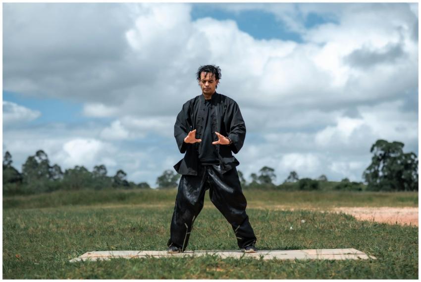 Man practicing martial arts outdoors in black unif