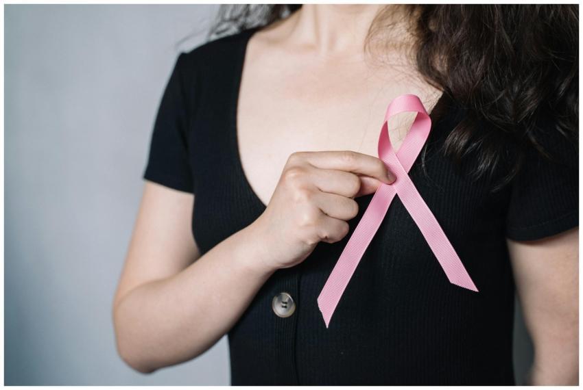 Close-up of a woman holding a pink ribbon symboliz
