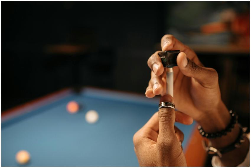Detailed close-up of hands chalking a billiard cue