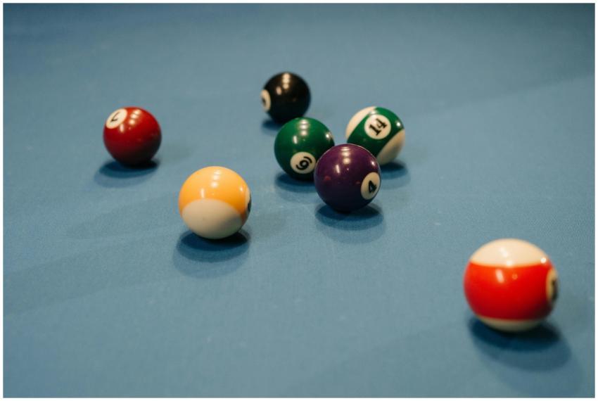 Colorful billiard balls scattered on a blue pool t