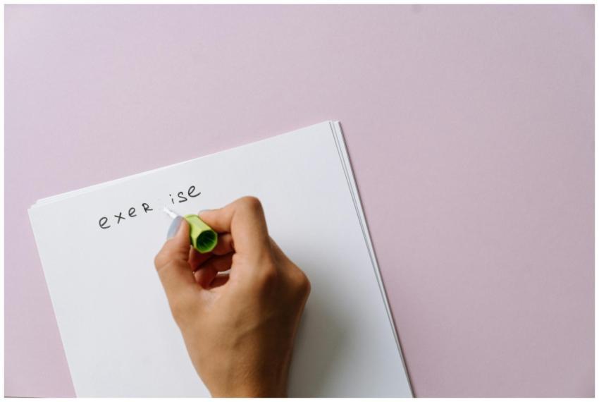 A hand using correction fluid to fix a spelling er