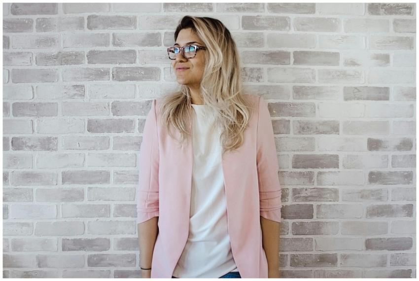 Elegant woman with glasses poses against a brick w