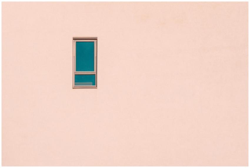 A minimalist pastel pink wall featuring a single r