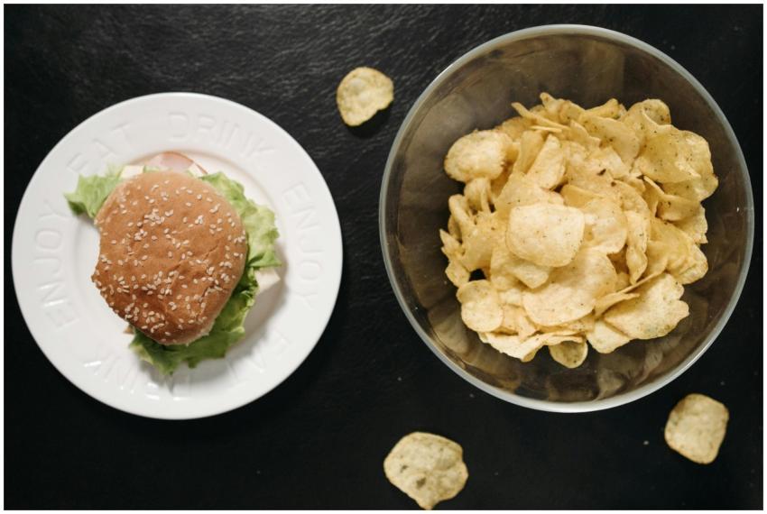 Close-up of a burger on a plate and bowl of chips