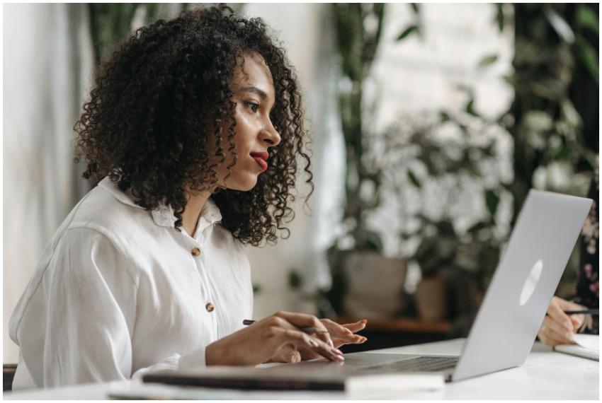 Young woman with curly hair typing on laptop in a